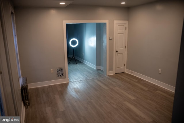 empty room with radiator heating unit and dark wood-type flooring