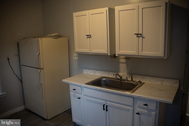 kitchen with sink, white cabinetry, dark hardwood / wood-style floors, white refrigerator, and light stone countertops