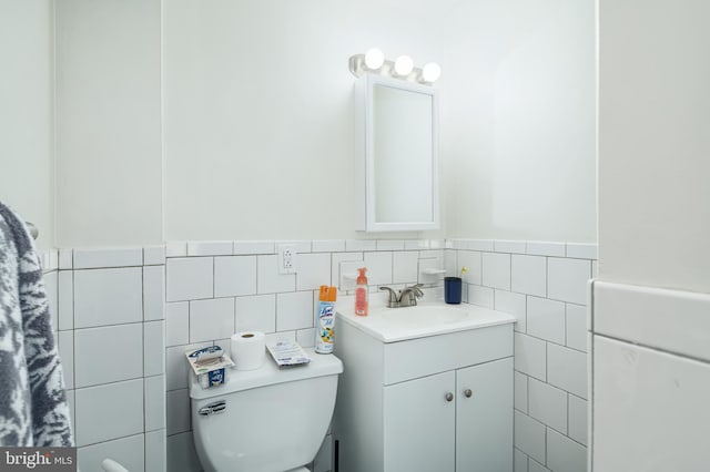 bathroom with vanity, toilet, and tile walls