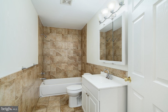 full bathroom featuring tiled shower / bath, vanity, toilet, and tile walls