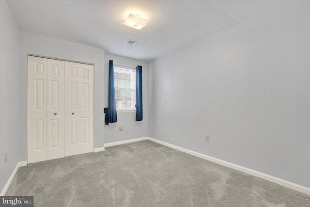 unfurnished bedroom featuring light colored carpet and a closet