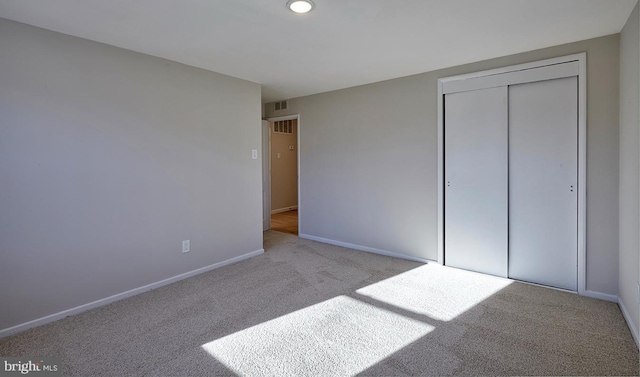 unfurnished bedroom with light colored carpet and a closet