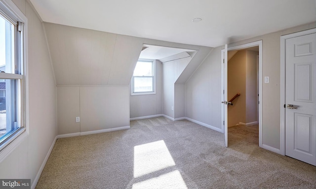 bonus room with lofted ceiling and light colored carpet