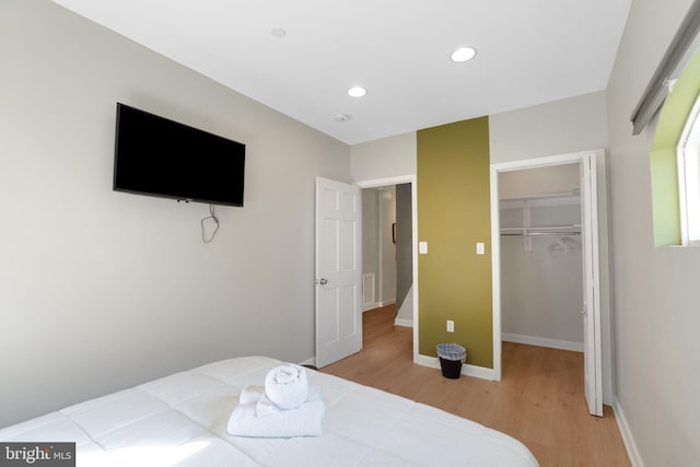 bedroom featuring a walk in closet, light hardwood / wood-style floors, and a closet