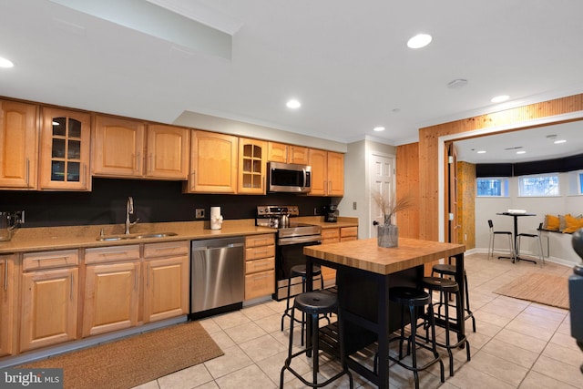 kitchen featuring sink, ornamental molding, light tile patterned flooring, and appliances with stainless steel finishes