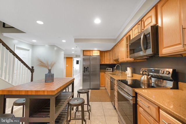 kitchen featuring sink, light tile patterned floors, ornamental molding, and appliances with stainless steel finishes