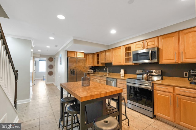 kitchen with light tile patterned flooring, appliances with stainless steel finishes, crown molding, and sink