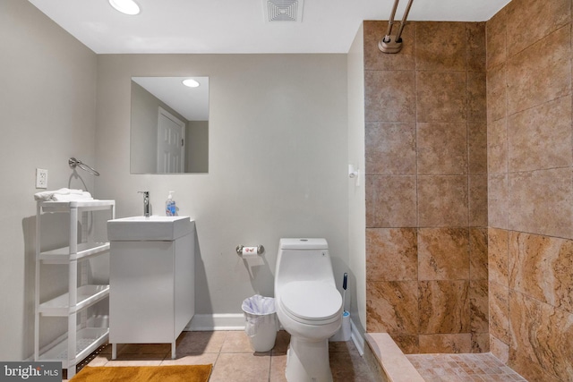 bathroom featuring tiled shower, sink, toilet, and tile patterned flooring