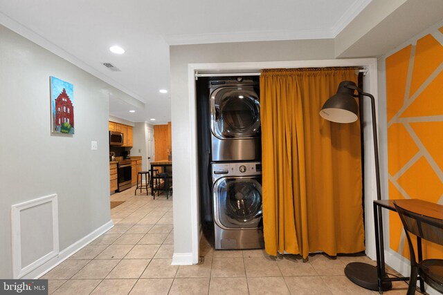 clothes washing area featuring ornamental molding, stacked washer and clothes dryer, and light tile patterned floors