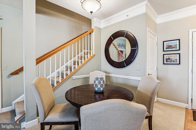 carpeted dining space with ornamental molding