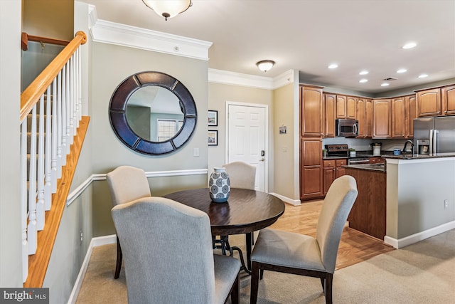 dining area featuring crown molding, sink, and light wood-type flooring