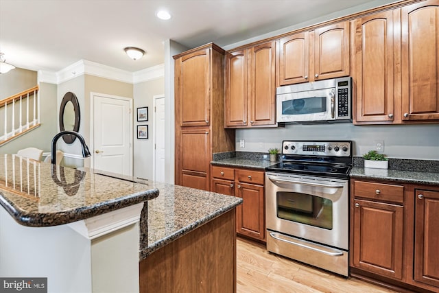 kitchen with appliances with stainless steel finishes, a center island, and dark stone counters