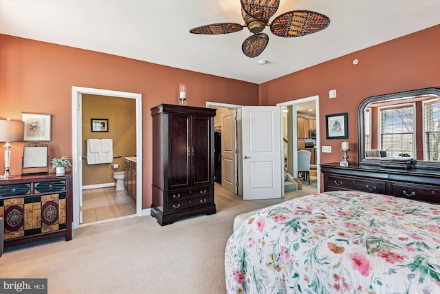 bedroom with ceiling fan, light colored carpet, and ensuite bath