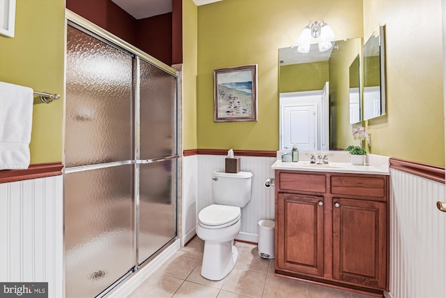 bathroom with tile patterned flooring, vanity, an enclosed shower, and toilet