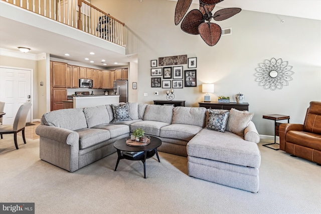 carpeted living room featuring a towering ceiling and ceiling fan