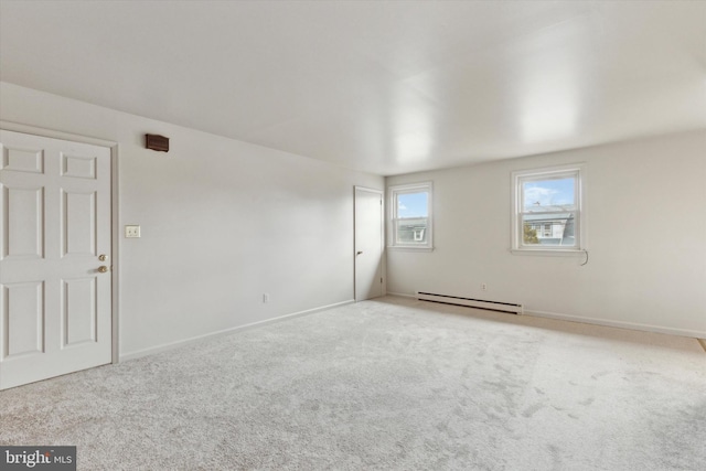 carpeted empty room featuring a baseboard heating unit