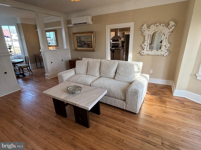 living room with wood-type flooring, decorative columns, and an AC wall unit