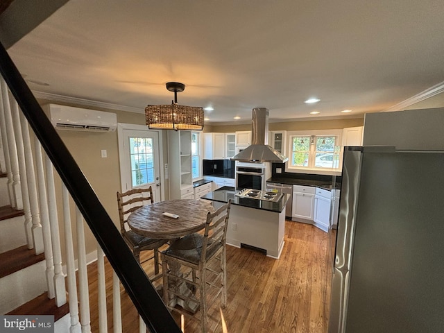 kitchen with white cabinetry, a wall mounted air conditioner, and island exhaust hood