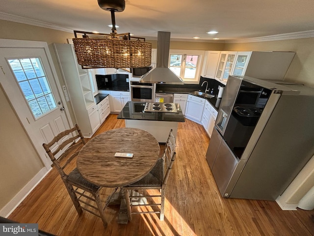 kitchen with appliances with stainless steel finishes, white cabinetry, sink, island exhaust hood, and light wood-type flooring