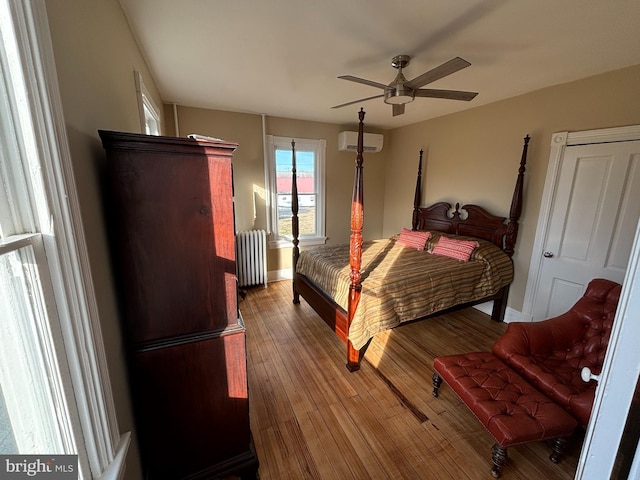 bedroom featuring hardwood / wood-style floors, ceiling fan, radiator heating unit, and a wall unit AC