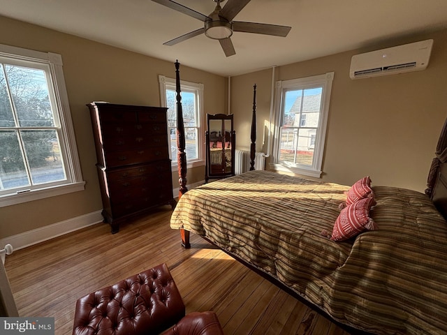 bedroom featuring an AC wall unit, radiator heating unit, ceiling fan, and light hardwood / wood-style flooring