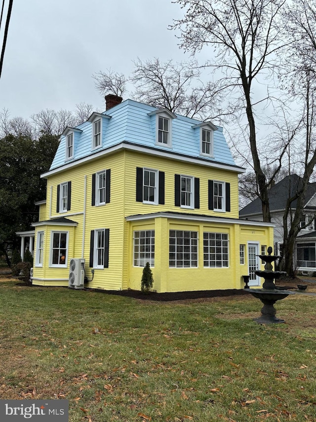 rear view of property with ac unit and a lawn