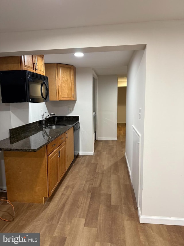 kitchen with dark stone counters, light hardwood / wood-style floors, sink, and black appliances