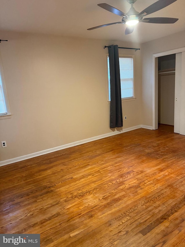 unfurnished bedroom featuring multiple windows, light hardwood / wood-style flooring, a closet, and ceiling fan