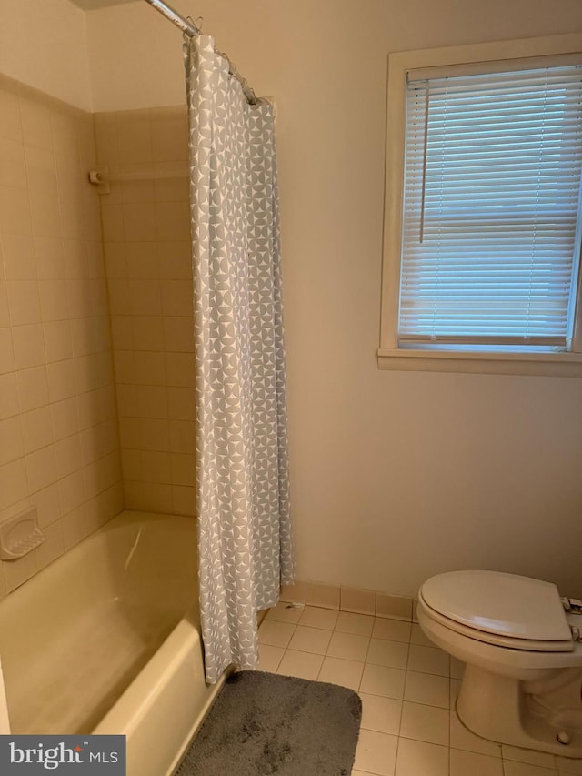 bathroom featuring shower / tub combo with curtain, tile patterned floors, and toilet