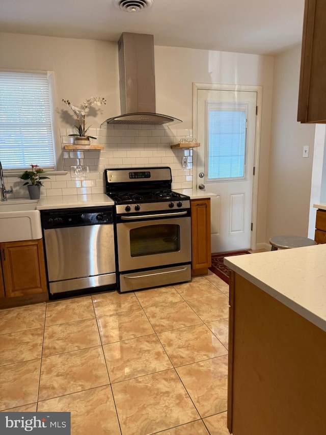 kitchen with sink, light tile patterned floors, appliances with stainless steel finishes, island range hood, and decorative backsplash