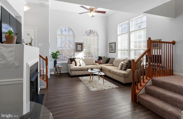 living room featuring ceiling fan, dark hardwood / wood-style floors, a high ceiling, and a wealth of natural light