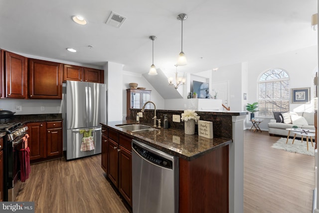 kitchen featuring sink, hanging light fixtures, a center island with sink, appliances with stainless steel finishes, and dark hardwood / wood-style flooring