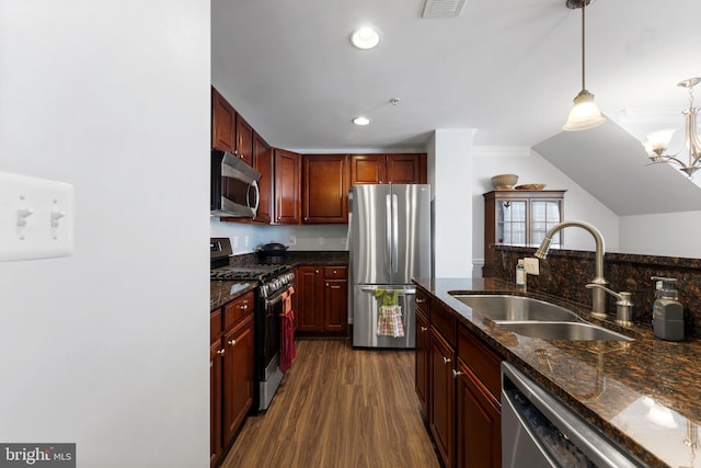 kitchen with sink, hanging light fixtures, stainless steel appliances, dark hardwood / wood-style floors, and dark stone counters