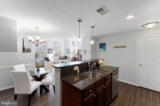 kitchen with dark wood-type flooring, sink, decorative light fixtures, stainless steel dishwasher, and dark stone counters