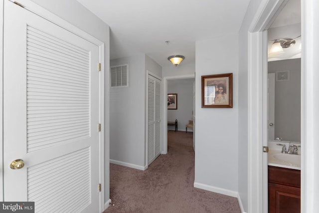 corridor with light carpet and sink