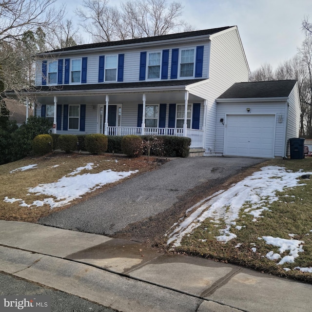 colonial home with a garage, a porch, and aphalt driveway