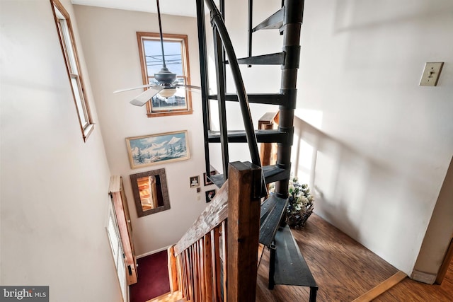 staircase featuring hardwood / wood-style flooring, a high ceiling, and ceiling fan