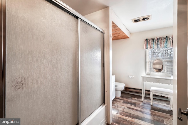 bathroom featuring wood-type flooring, combined bath / shower with glass door, and toilet