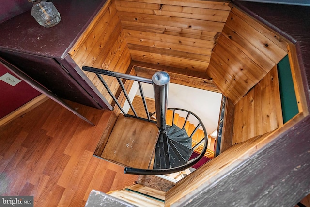 staircase featuring hardwood / wood-style flooring, lofted ceiling, and wooden walls