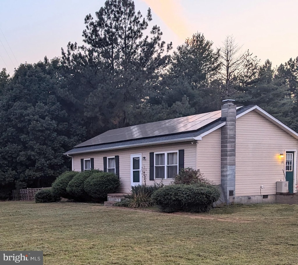 view of front of property featuring a yard, solar panels, and central air condition unit