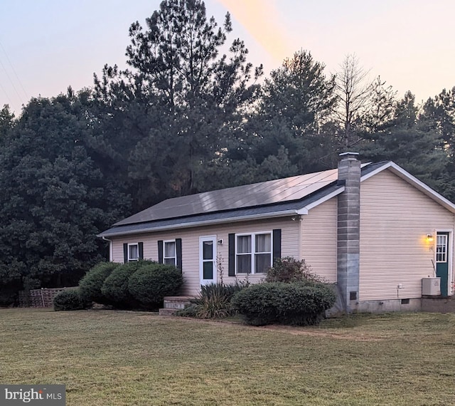 view of front facade with crawl space, central air condition unit, roof mounted solar panels, and a front lawn