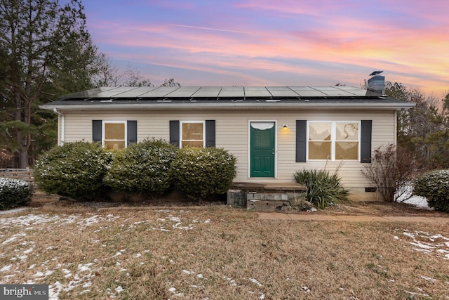 manufactured / mobile home with roof mounted solar panels, a yard, a chimney, and crawl space