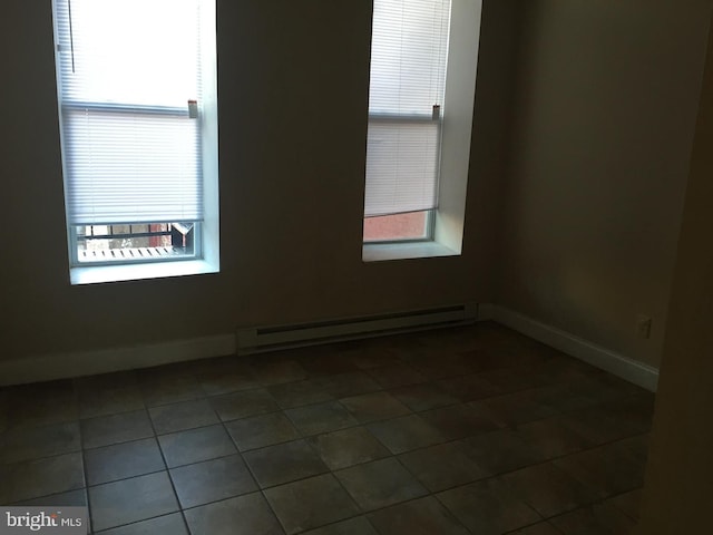 unfurnished room with baseboard heating and dark tile patterned flooring