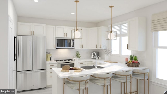 kitchen with a peninsula, white range with gas stovetop, freestanding refrigerator, a sink, and white cabinets