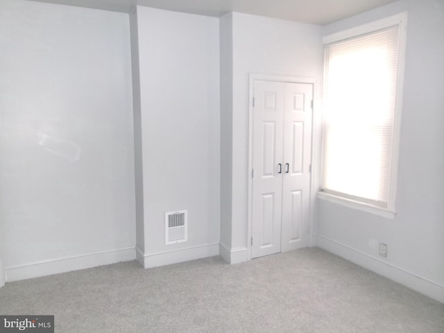 unfurnished bedroom with light carpet and a closet