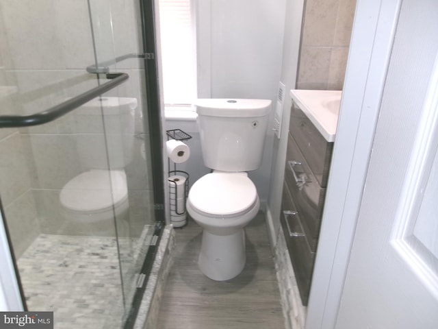 bathroom with a shower with door, vanity, tile walls, and toilet