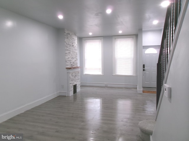 unfurnished living room with a stone fireplace and hardwood / wood-style floors