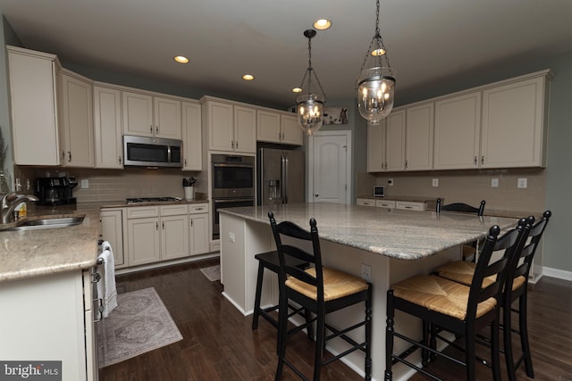 kitchen with sink, a breakfast bar area, hanging light fixtures, a center island, and stainless steel appliances