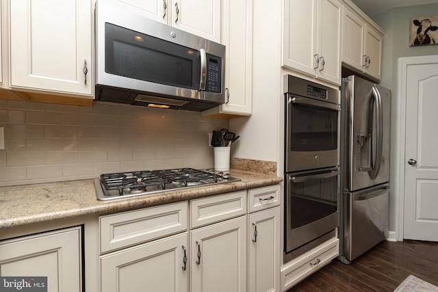 kitchen featuring dark wood-type flooring, appliances with stainless steel finishes, light stone countertops, and tasteful backsplash