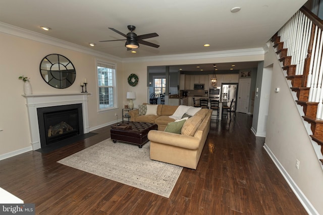 living room with dark wood-type flooring, ornamental molding, and ceiling fan